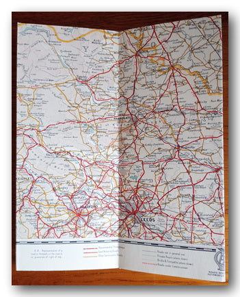 Folded map with road networks and labels, framed ion a table.