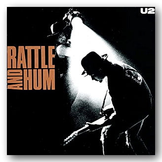 Album cover for 'Rattle and Hum' by U2 with a black and white photo of two people.